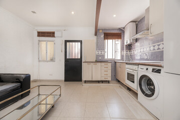 Kitchen open to the living room furnished in a loft with built-in white appliances, white cabinets