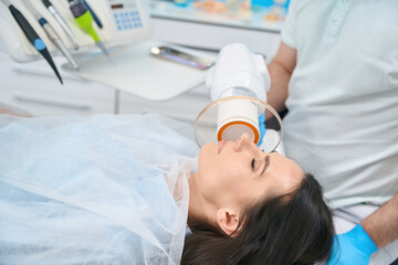 Naklejka premium Professional dentist in dental office puts photopolymer filling on woman