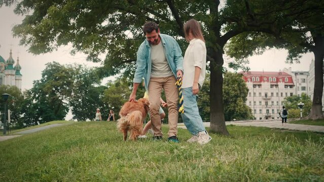Positive daughter runs with dog while parents stand on grass