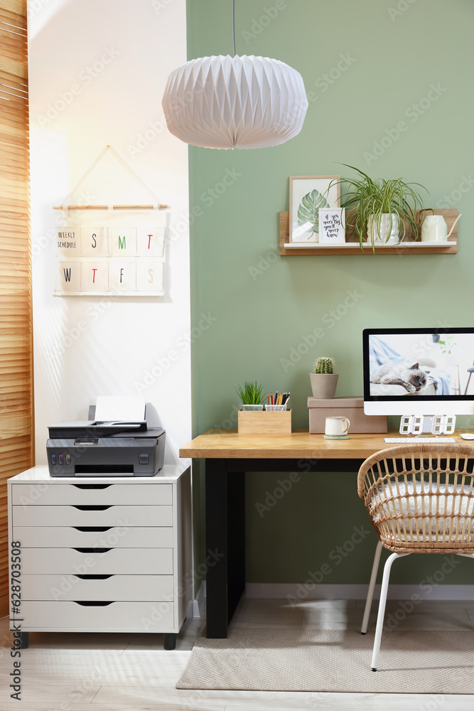 Poster Stylish workplace with computer, printer and houseplant near olive wall at home