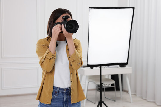 Professional photographer taking picture in modern photo studio, space for text