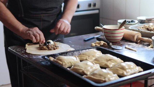 Culinary Tradition: Latin Elderly Woman Crafting Delicious Chilean Baked Empanadas de Pino in her Home Kitchen