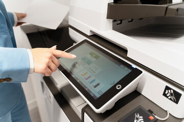 Successful employee, secretary, printing out documents on printer, using control panel