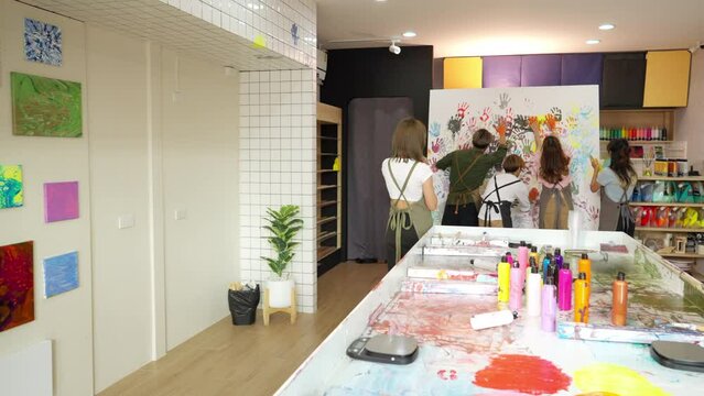 Group of Asian generation z people learning acrylic painting art by hand on canvas workshop at art studio. Young artist university student enjoy and fun creating colorful abstract modern art in class.