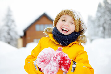 Happy preteen boy having fun playing with fresh snow during vacation in european Alps. Child...