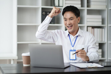 Fototapeta na wymiar Happy young businessman looking at laptop excited by good news online.