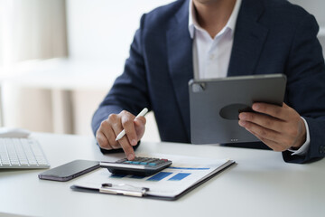 Close up view of businessman working in the office room while using calculator in the office room.