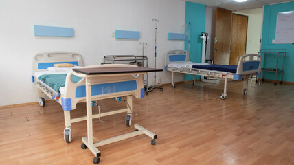 camas de hospital sin pacientes sobre piso de madera dentro de hospital - obrazy, fototapety, plakaty