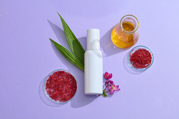 Top view of cosmetic mockup bottle with natural ingredient - saffron, flower, green leaves and yellow liquid on purple background. Saffron is a wonderful elixir for both health and beauty.