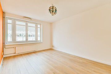 an empty room with wood flooring and white walls, there is a chandel lamp hanging on the wall