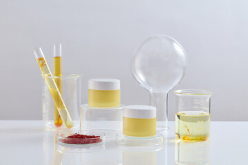 Two yellow jars placed on transparent podiums. A petri dish of saffron, test tubes and a beaker of...