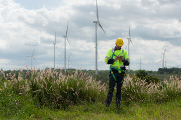 Engineers are using a smartphone to check the wind turbine in the field, The concept of natural energy from wind.