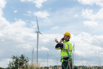 Engineers are using a smartphone to check the wind turbine in the field, The concept of natural energy from wind.