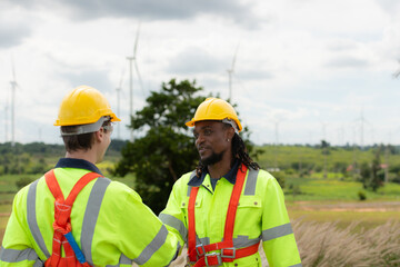 Engineer and technician discussing a solution problem of wind turbine before go in and check wind turbine, The concept of natural energy from wind.