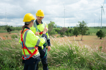 Engineer and worker discussing the project on the background of wind turbines