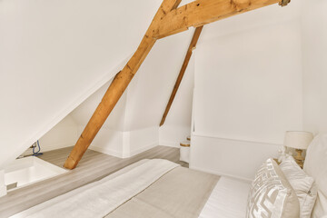 an attic bedroom with white walls and wood beams on the ceiling, there is a bed in front of it