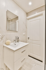 a bathroom with marble flooring and white walls, along with a large mirror on the wall above the sink