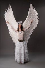 White angel with wings rising her heands and looking up the sky