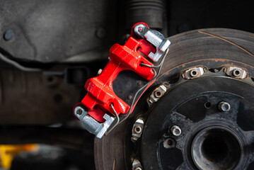 Car mechanic or serviceman disassembly and checking a disc brake and asbestos brake pads for fix and repair problem at car garage or repair shop