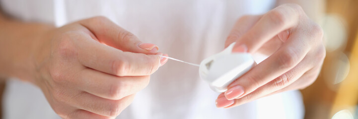 Dental floss for dental care in hands of woman close-up.
