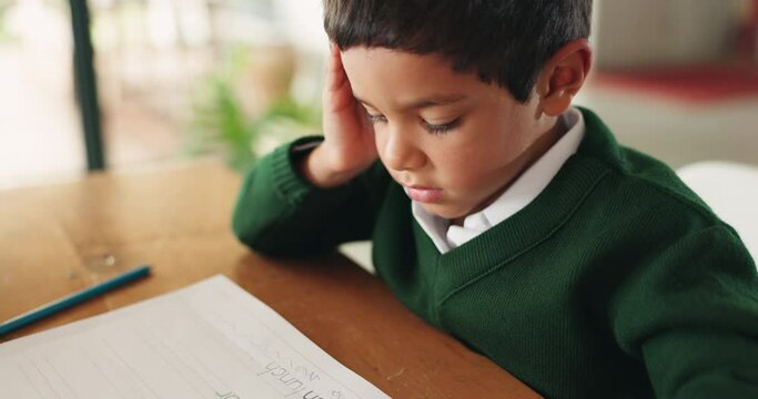 Bored, education and boy child doing homework, assignment or project in the dining room at home. Tired, sleepy and little kid student working on school work with books by the table of a modern house.