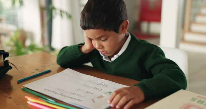 Tired, bored and boy child doing homework, assignment or project in the dining room at home. Burnout, sleepy and little kid student working on school work with books by the table of the modern house.