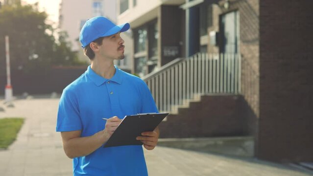 Caucasian Real Estate Agent in Blue Uniform Describing Apartment and Taking Notes About the Empty Property While Walking in the New Cottage City. Realtor Working, Writting the Data