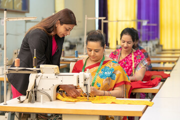 Young Indian designer doing guidance to women group at textile factory.