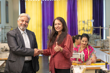 Senior businessman shake hand with female colleague at textile factory.