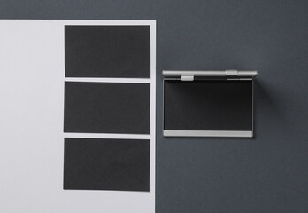 Metal box business card holder with black business cards on white gray background