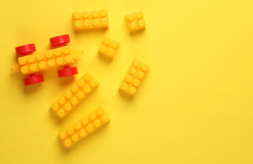 Colored bricks of children's constructor on yellow background. Top view