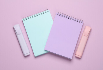 Markers or colored felt-tip pens with notebooks on pastel background. Creative layout. Top view