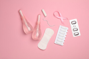 Women's health concept. Vaginal enemas, pad, tampon, pills and pink awareness ribbon on pink...