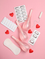 Obraz premium Women's health concept. Vaginal enemas, pad, tampon, pills and hearts on pink background. Flat lay
