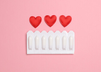 Blisters of vaginal suppositories, hearts on a pink background