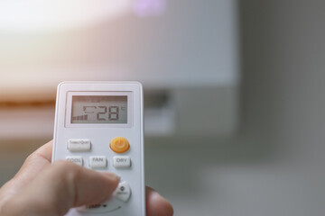 Close-up picture of adjusting the air conditioner temperature with a remote control in the room at home