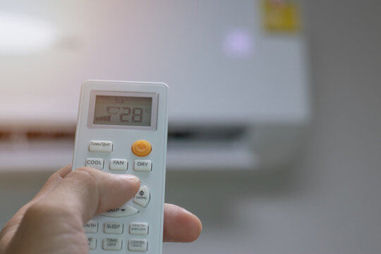 Close-up picture of adjusting the air conditioner temperature with a remote control in the room at home