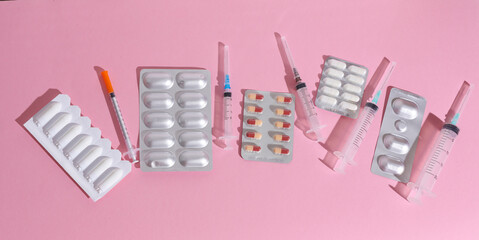 Various medicines, blisters of pills with syringes on a blue-pink background. Creative layout, minimalism medicine concept