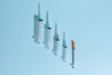 Different medical syringes on blue background with shadow. Minimalism medical layout
