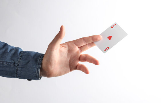Man's hand in denim shirt holding Ace of Hearts on gray background