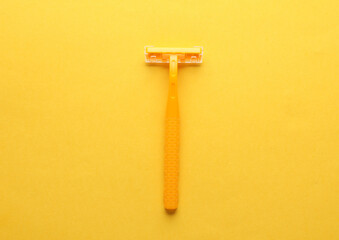 Yellow razor on a yellow background. Top view