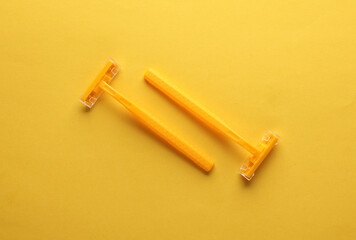 Two yellow razors on a yellow background