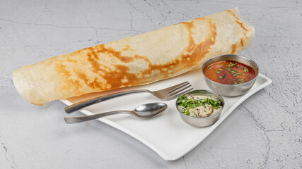Plain Dosa – A South Indian pancake in white plate with chutney and sambhar (curry) garnished and styled, on textured background