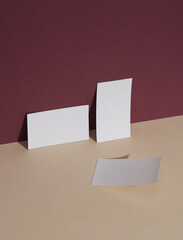 White business cards on burgundy beige background with shadow. Creative layout. Minimal business mockup