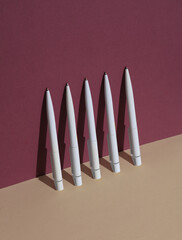 White Pens on burgundy beige background. Minimalism, conceptual business or education photo,...