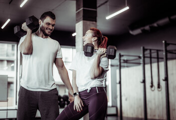 Smiling woman and man athlete with dumbbells in the gym. Healthy lifestyle