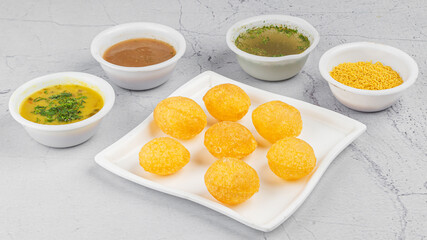 Pani Puri OR Golgappa is a popular Indian Chat menu, selective focus in white plate with green, red, imli chutney, turmind
