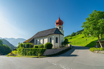 das Dorf Marul im Grosswalsertal mit seiner markanten Kirche mit rotem Zwiebelturm. Sommer im Natura 2000 Gebiet.  - obrazy, fototapety, plakaty