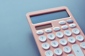 close up modern peach colour pastel calculator and white button on blue background, business and finance accounting concept