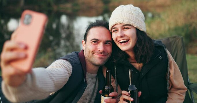 Selfie, camping and couple with beer by a river for a celebration and to update social media of a vacation together. Internet, travel and people happy for a online picture in the outdoor woods